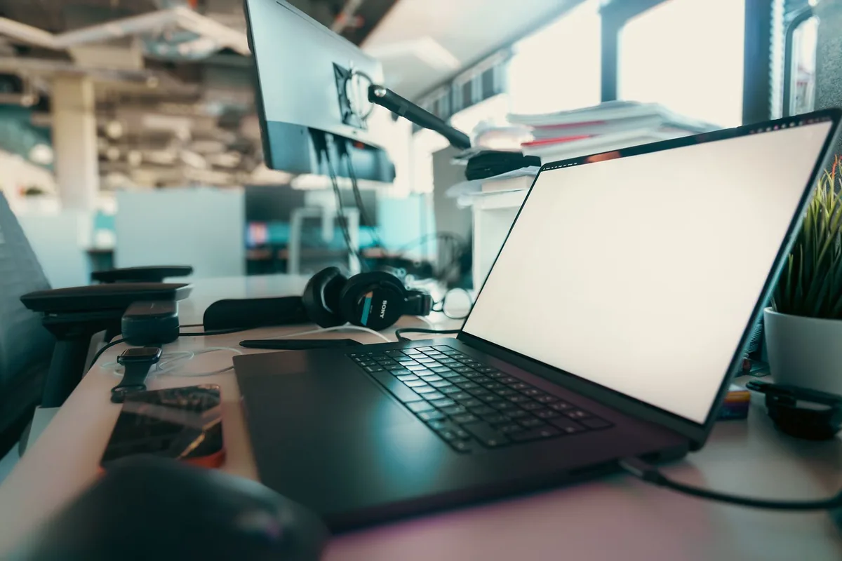Laptop, monitor and headphones arranged on a working desk.