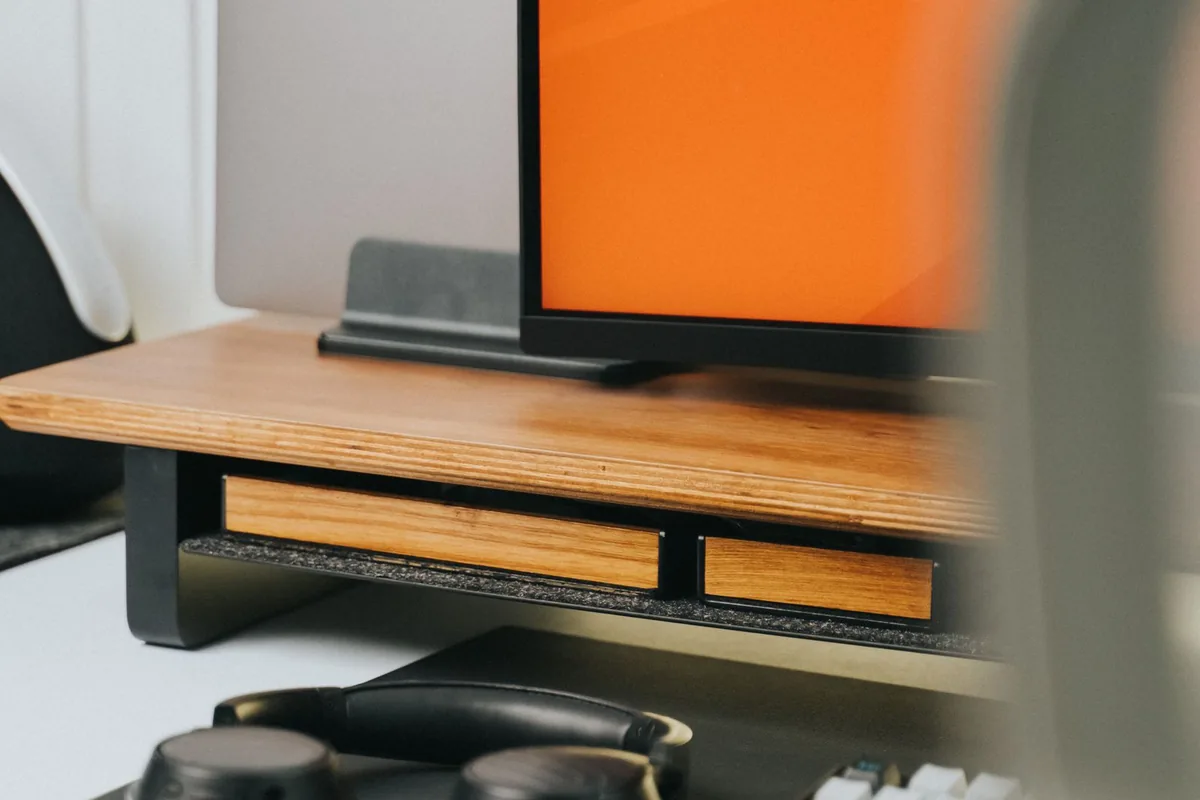 Monitor and headphones on a compact wooden home-office desk.