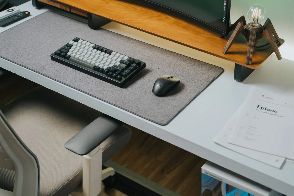 Wireless keyboard and mouse arranged on a wooden desk.