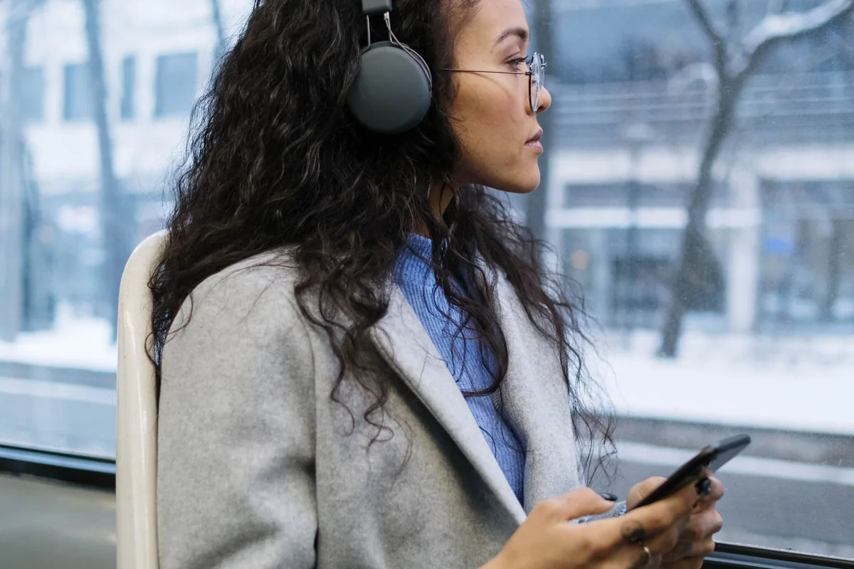 Woman wearing over-ear headphones while seated on public transport.