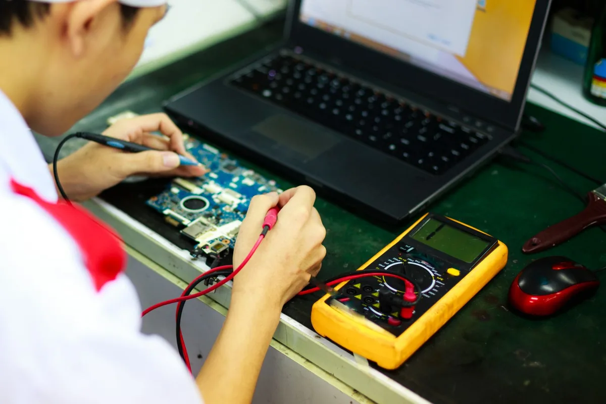 Technician working on a laptop with diagnostic tools.