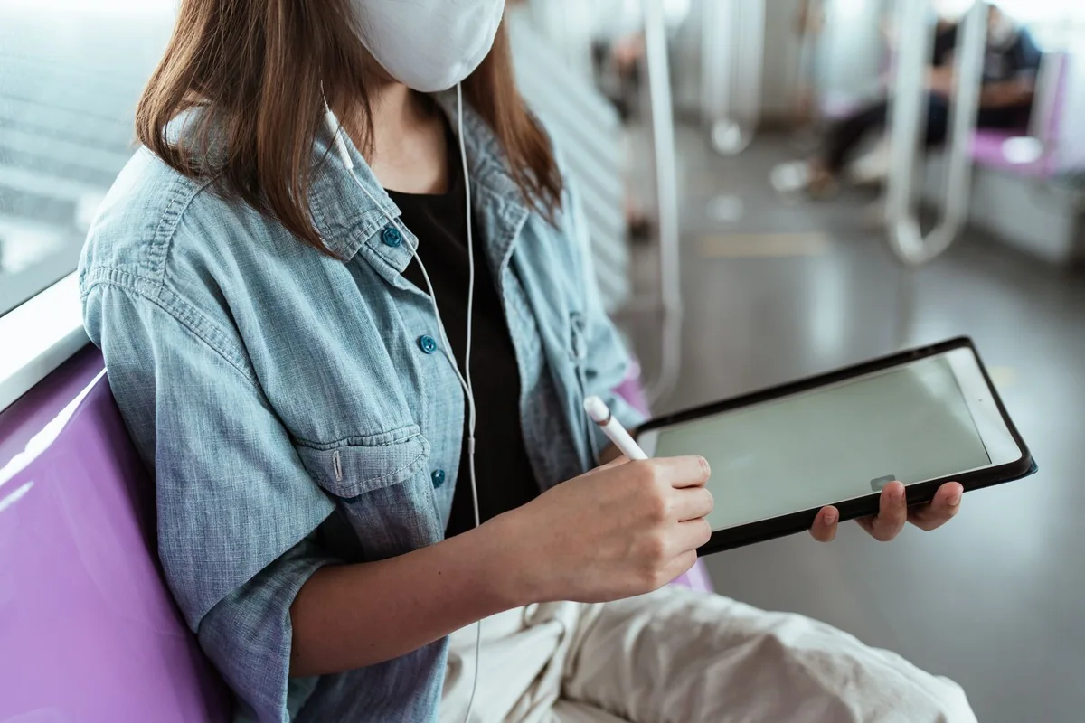 Passenger using a tablet and stylus while travelling on public transport.