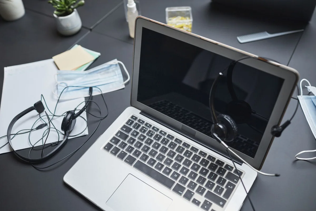 Headphones resting beside a laptop and everyday office supplies.